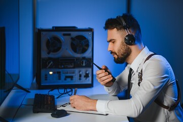 Secret agent listens on the reel tape recorder. Officer wiretapping in headphones