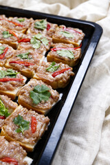 Minced pork toast on black tray with crumpled tablecloth in vertical. Close-up miced pork toast preparing for frying. Deep-fried food, homemade, Thai style eating, cooking, chili, menu, and texture.