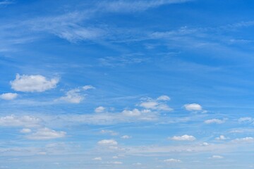 The image features a bright blue sky with scattered fluffy white clouds, creating a serene atmosphere. It captures the essence of a perfect day, ideal for backgrounds and relaxation.