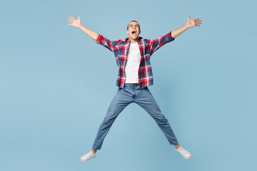 Full body young middle eastern man wear red shirt casual clothes jump high with outstretched hands legs look camera isolated on plain pastel light blue background studio portrait. Lifestyle concept.