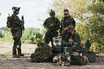 A team of servicemen finalizes mission details, checking maps, logging data into the system,...