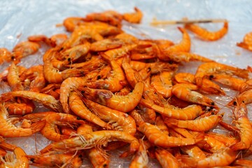 A stunning pile of freshly cooked tiger prawns sitting elegantly on a bed of ice, perfectly prepared and ready to be served to seafood lovers, highlighting their vibrant color and freshness.