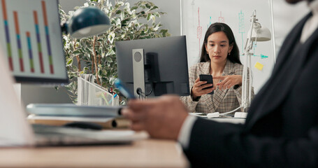 Office workers sit at their desks in front of computer monitors, not attending to their duties, using their phones browsing social media scrolling through pages chatting with friends break from work