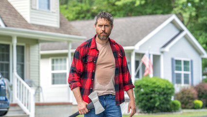 Lumberjack at backyard with an ax. Lumberjack with heavy axe. Strong sweating man after hard work....