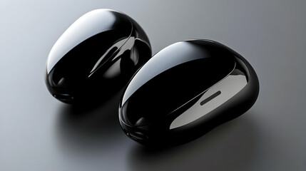 Two black, glossy, earbud cases or charging cases on a gray surface.
