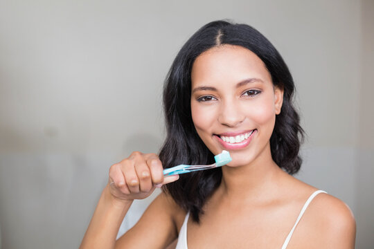 Smiling woman brushing teeth at home, promoting dental hygiene and wellness