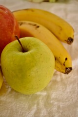 Ripe apples and bananas lie on a white tablecloth