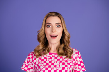 Surprised young woman in a pink checkered top on a vibrant purple background