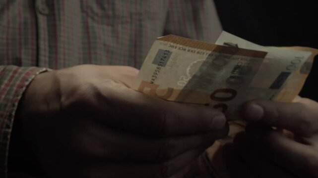 A man in an old shirt counting money.