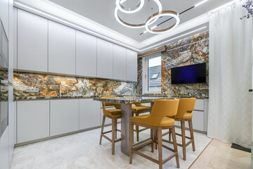 Kitchen with exclusive design and beautiful decoration. White kitchen set, stylish chandelier above the table with bar stools.