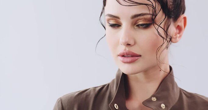 Close-up face of a girl with bright fashionable make-up. Beautiful young woman  with stylish hairstyle posing at studio. Sexy girl with green eyes. Fashion model with beautiful eyes. Real time