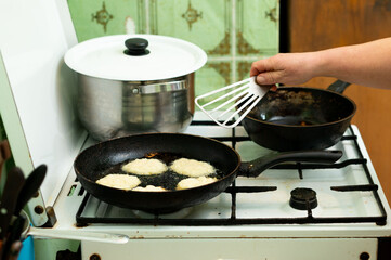 Perfectly golden crispy fritters sizzle on the stove as a skilled hand uses a spatula to expertly flip each piece in a cozy kitchen at midday