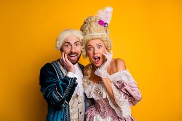 Elegant Couple in Historical Masquerade Costumes Expressing Delight Against Yellow Background
