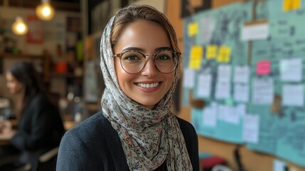 Smiling woman in hijab and glasses at office.