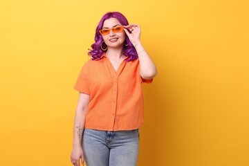 Beautiful woman with bright purple hair on orange background