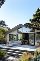 Fototapeta premium Modern coastal home with large windows surrounded by greenery in bright daylight, showcasing outdoor deck and inviting space for relaxation