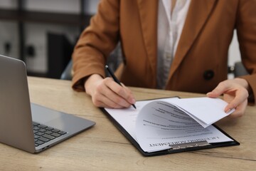 Fototapeta premium Woman signing licensing agreement document at wooden table indoors, closeup
