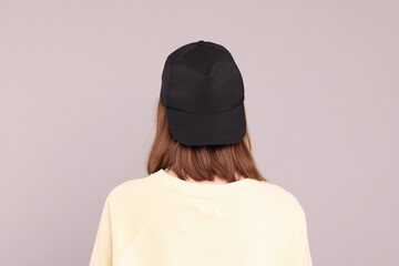 Woman in stylish baseball cap on grey background, back view. Mockup for design