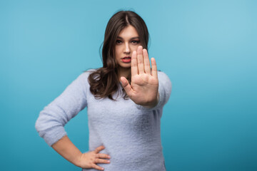 Confident woman extending hand assertively, expressing rejection or denial. Ideal for themes of boundaries, refusal, communication, and assertiveness in professional and personal contexts on vibrant