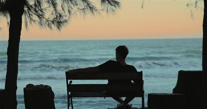 Man relaxing on bench by ocean, silhouette, sunset, tranquil scene, peace, solitude, nature