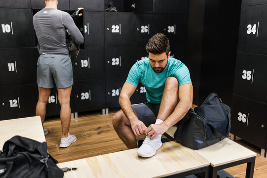Two man prepare for a training in the dressing room of the gym.