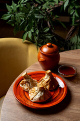 Savor the rich flavors of Georgian cuisine with perfectly steamed khinkali, presented on a vibrant orange plate. A cozy atmosphere enhances this culinary experience, perfect for sharing