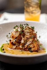 A beautifully arranged dish featuring tender ingredients garnished with sliced almonds, vibrant herbs, and rich sauces, showcasing the culinary artistry of a European restaurant