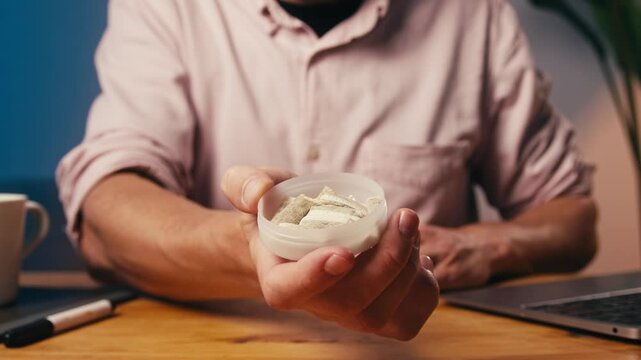 Snus nicotine tobacco close up, pack of tobacco for gum. unhealthy addiction. Man opening box with snus and taking one. 