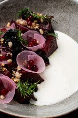 Dine on a beautifully plated dish of European cuisine, showcasing vibrant beetroot slices adorned with delicate edible flowers, nuts, and drizzled with a creamy sauce at an upscale restaurant