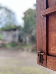 Window to the World: A partially open wooden window frames a blurred outdoor scene, blending the rustic charm of the window with the natural beauty visible through it.
