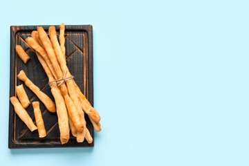 Wooden board with bunch of tasty Italian Grissini on blue background