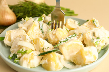 Plate of tasty Potato Salad with greens on yellow background, closeup