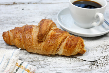 kruvasan cup of coffee and croissant on a rustic white wooden	