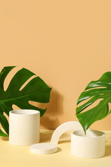 Plaster podiums and monstera leaves on beige background