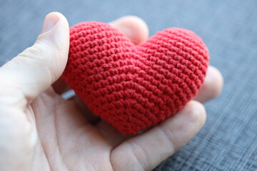 Fototapeta premium A person holding a handmade crochet heart, perfect for expressing love and affection.