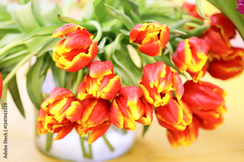 Poster a decorative vase filled with a variety of bright red and yellow flowers, perfect for adding a pop o