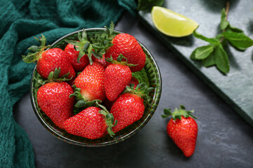 Bowl with ripe strawberry on dark background, closeup