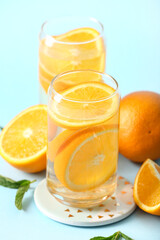 Glasses of infused water with orange slices on blue background