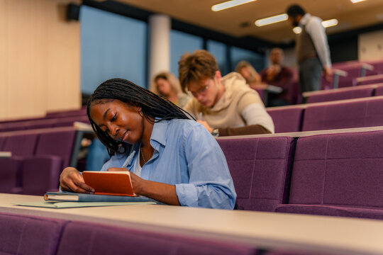 University student taking notes during lecture in auditorium