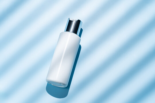 Top view of a cosmetic bottle on a blue striped background