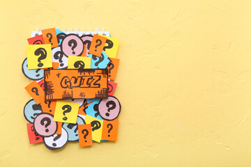 Notebook with quiz card and question marks on yellow background
