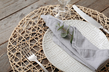 Beautiful table setting with cutlery and eucalyptus branch in napkin on wooden table