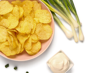 Bowl of tasty sour cream with green onion and potato chips on white background