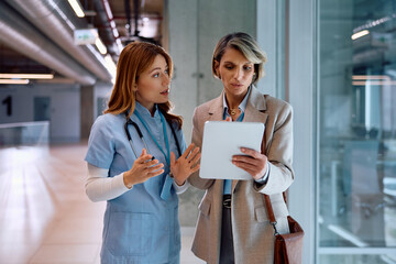 Businesswoman and female nurse using digital tablet at medical clinic.