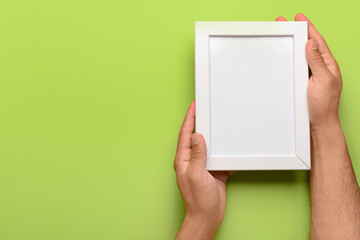 Man holding blank photo frame on green background
