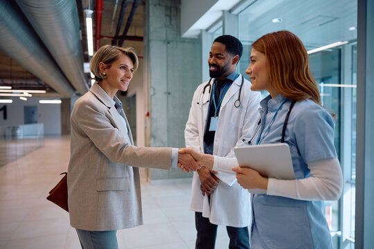 Smiling medical sales representative greeting healthcare workers at clinic.