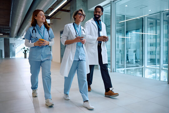 Multiracial group of happy doctors going on coffee break while working at medical clinic.