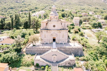 Church of the Our Lady Birth among green trees. Prcanj, Montenegro. Drone