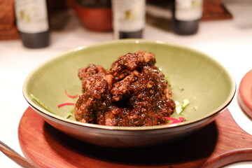 a dish of fried chicken pieces coated in a rich, dark, and glossy sauce