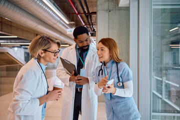 Happy doctors using cell phone on coffee break at medical clinic.